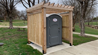 Portable restroom inside wooden arbor