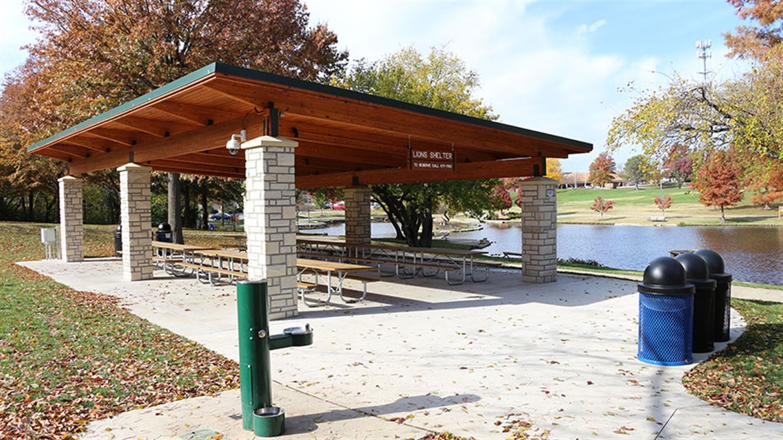 Park shelter with drinking fountain and trashcans overlooking pond