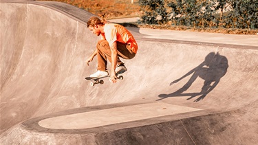 Male skateboarder airborne in skate park flow bowl