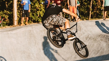 Male bicyclist airborne in skate park flow bowl