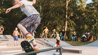 Female skateboarder on stair handrail at skate park