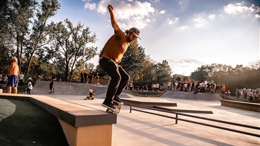 Male skateboard balanced on edge of concrete wall at skate park