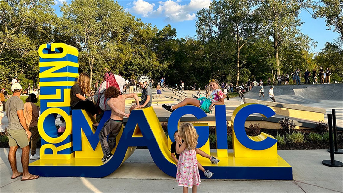 People standing and posing on Rolling Magic sign
