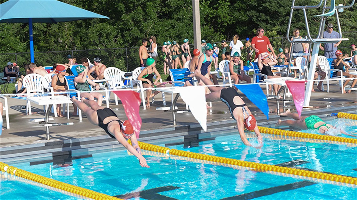 kids diving into pool during swim meet