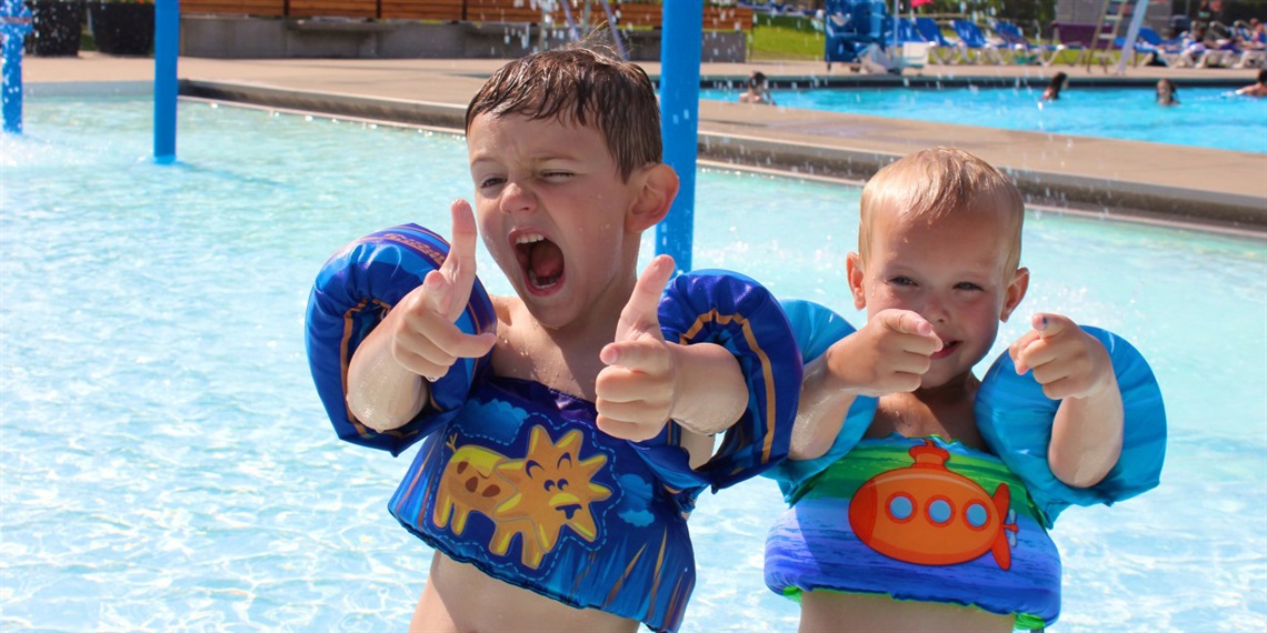 Two boys giving a thumbs up at the pool