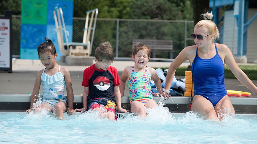 swim lessons instructor shows kids how to kick their feet in water