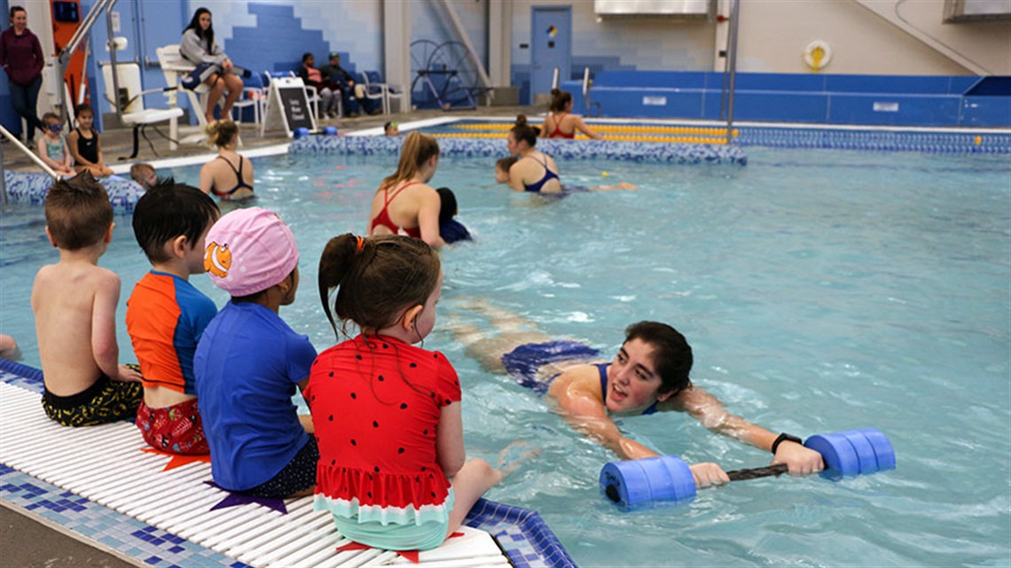 swim lessons instructor demonstrating flotation device to kids