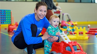 Adult and child playing with push toy during Gym for Me