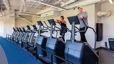 Woman and man using stair climber machines