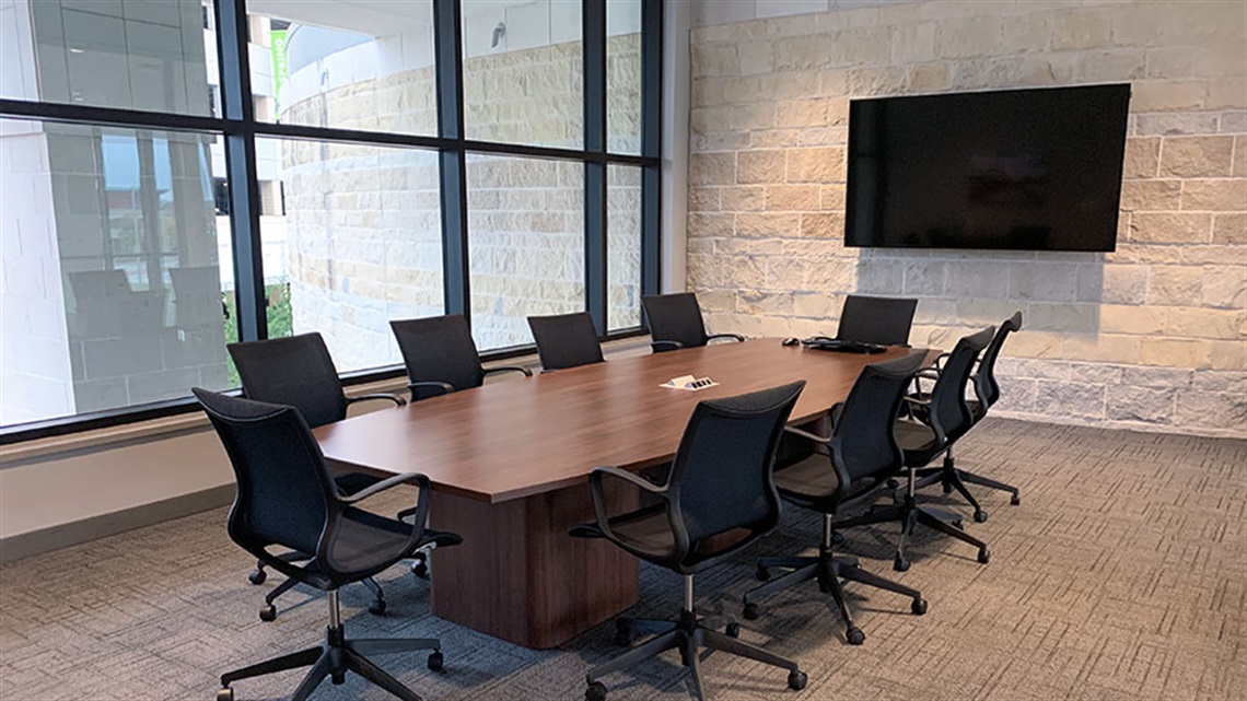 conference table, chairs and monitor on wall in conference room