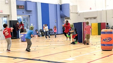 Families playing Nerf Battlezone in gym