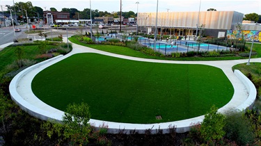 Bird's-eye view of oblong turf area with pickleball courts in background