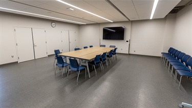 Angled view of tables and chairs facing TV and chairs along one wall