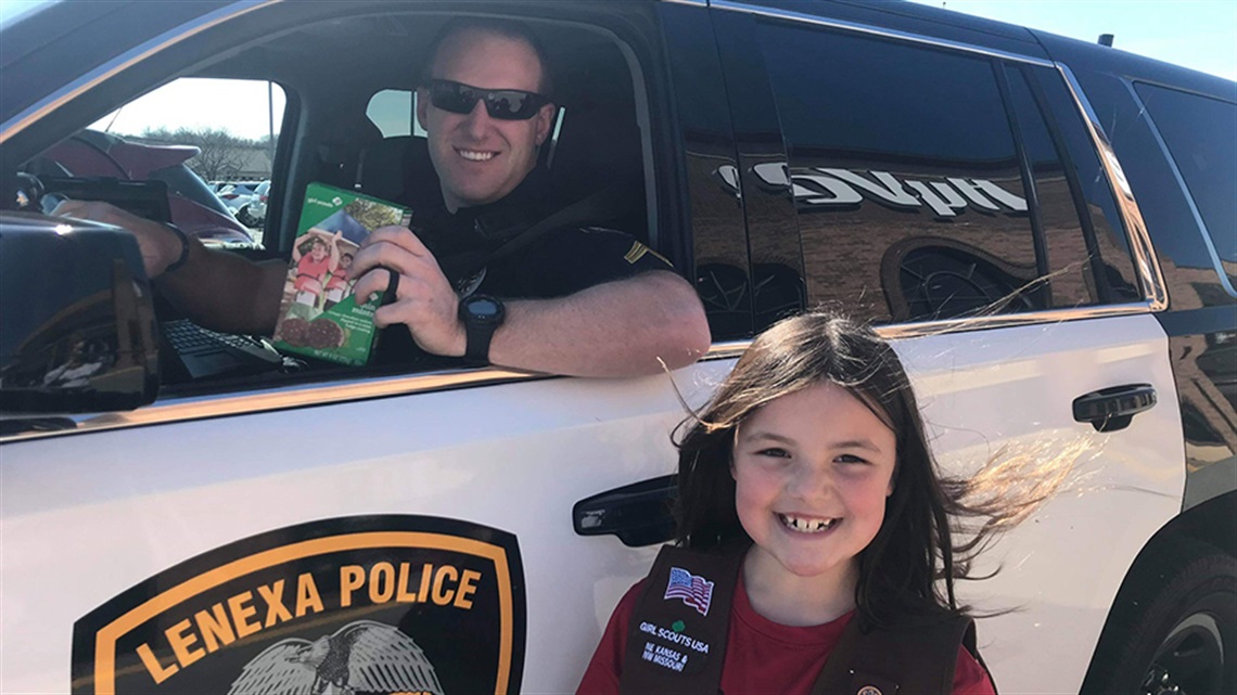 Police Officer in car with girl scout nearby