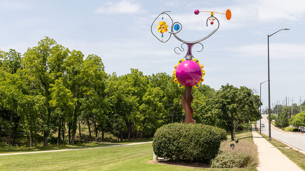 Whimsical, colorful depiction of an abstract bicycle atop a glass ball.