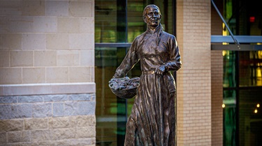 Bronze piece of Lenexa’s namesake holding a basket of produce and a walking stick