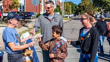 Volunteer hands out spoons for sampling chili and salsa