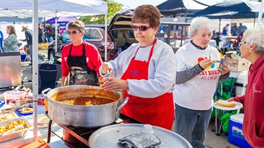 Woman in apron stirring pot of chili