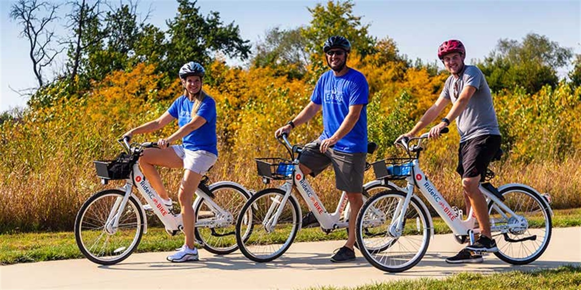 three people standing on trail with electric-assist bikes