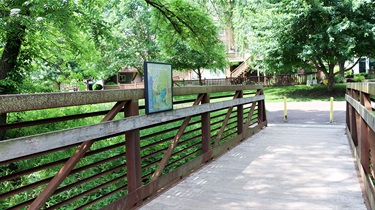Walking tour sign on railing of bridge along riparian corridor