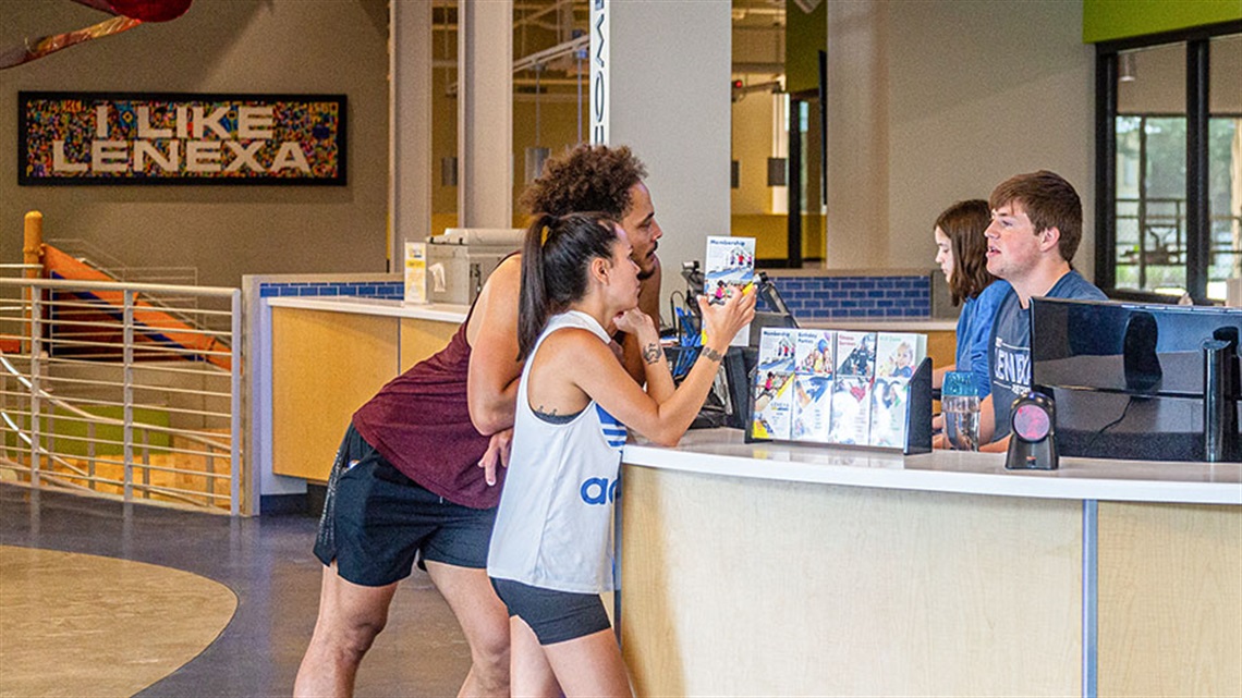 man and woman asking questions at Lenexa Rec Center welcome desk