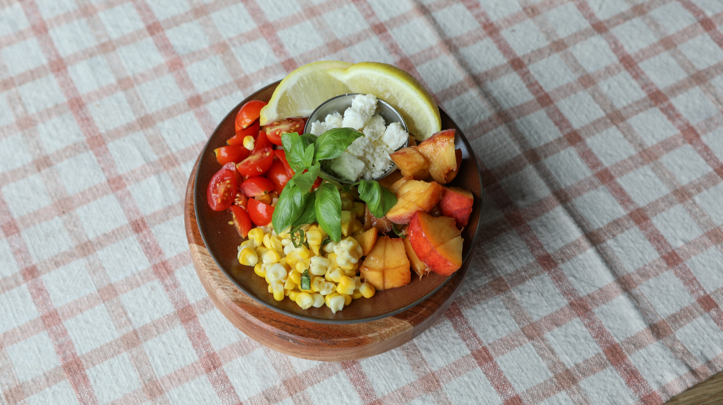 Brown plate with summer sweet corn, tomatoes and peaches
